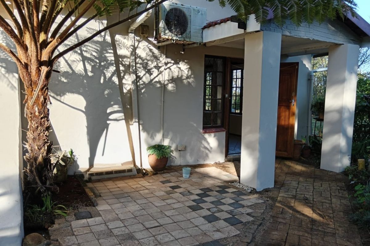 Rear exterior view of the property featuring a paved patio area, concrete support pillars, and an installed air conditioning unit.