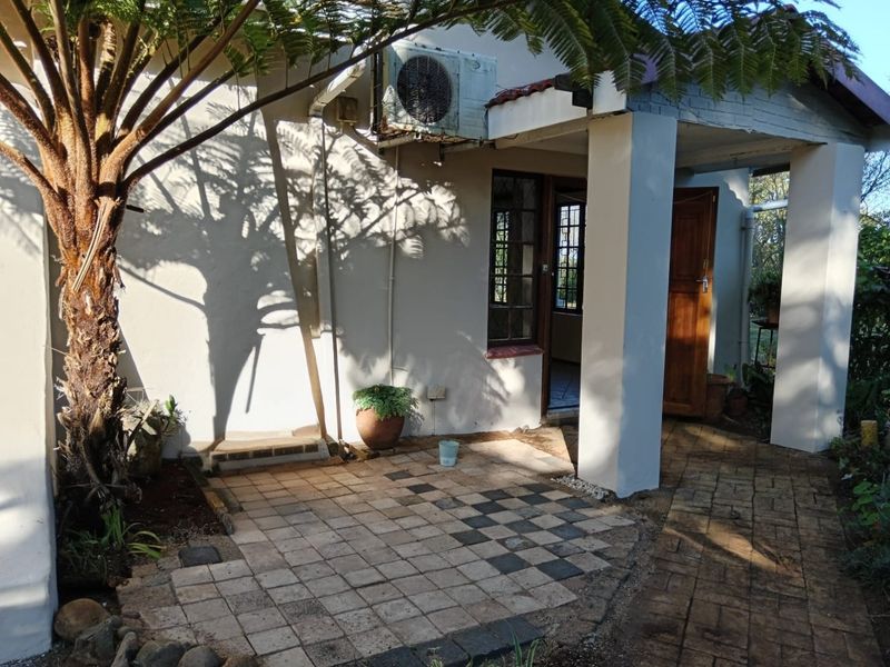 Rear exterior view of the property featuring a paved patio area, concrete support pillars, and an installed air conditioning unit.