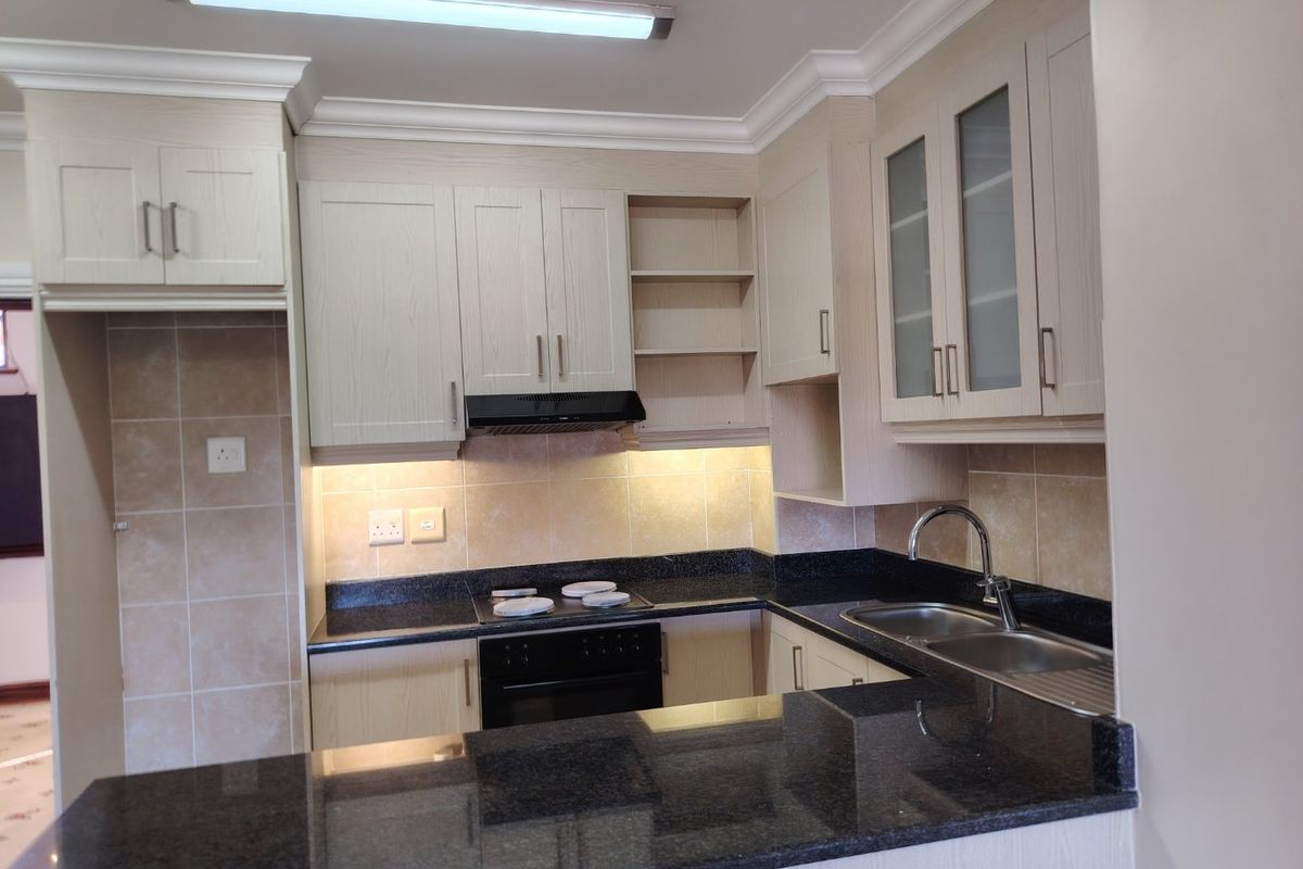 A well-maintained kitchen featuring light wood cabinetry, granite countertops, a built-in oven with extractor fan, and a double stainless steel sink.