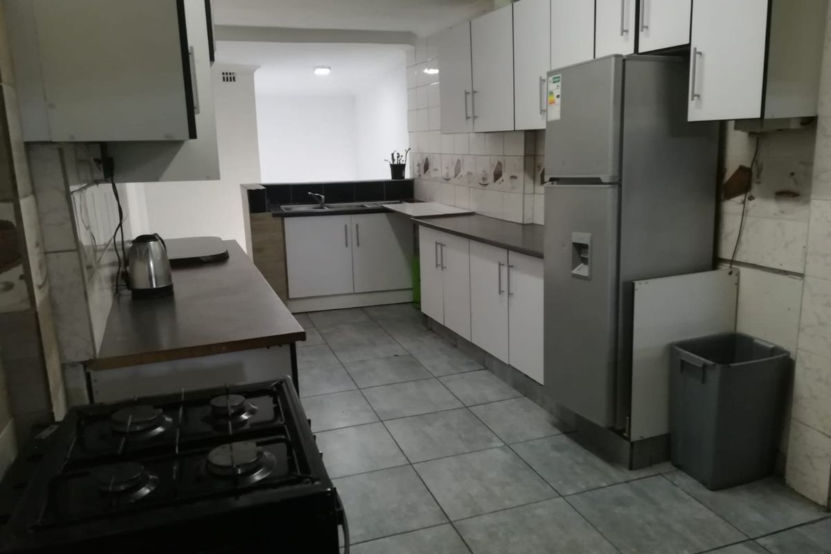 A functional kitchen featuring white cabinetry, tiled flooring, and a gas stove, offering a practical layout for daily meal preparation.