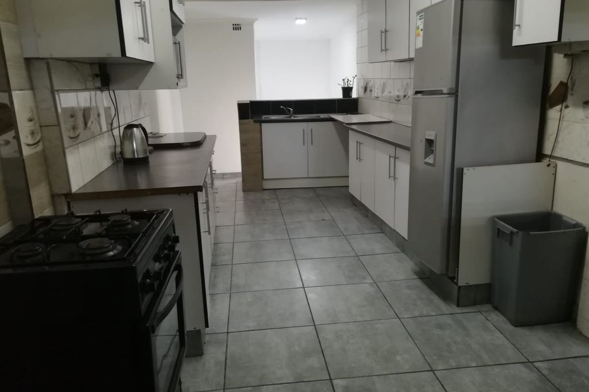 A functional kitchen featuring tiled flooring, white cabinetry, a gas stove, and a stainless steel sink with a laminate countertop.