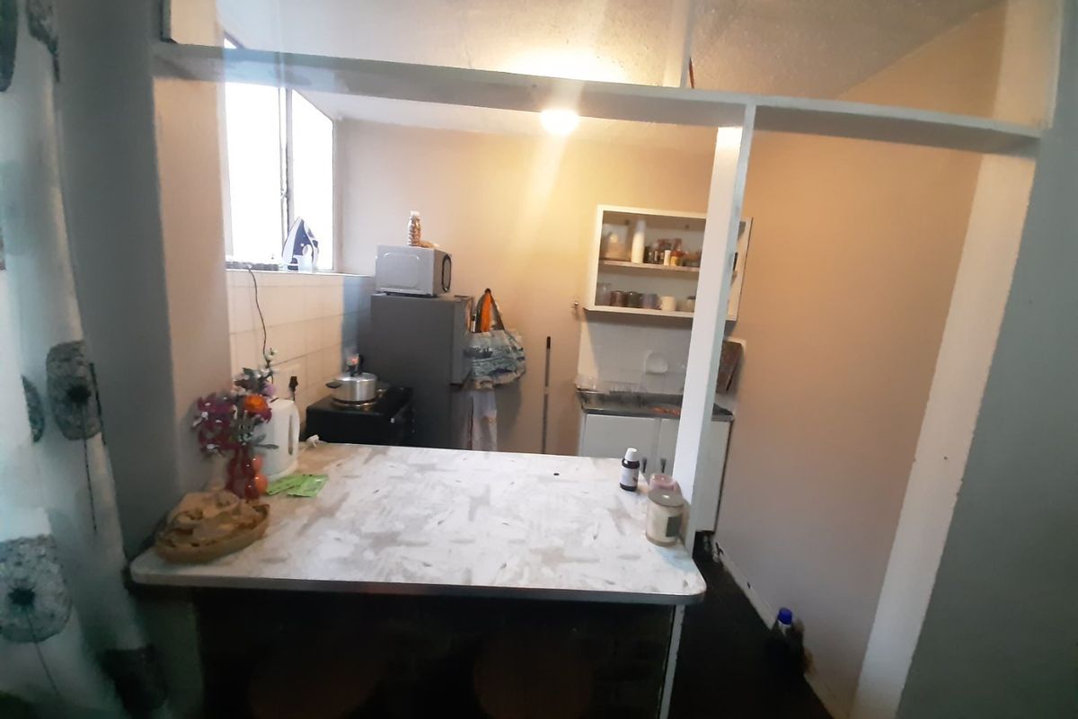 A compact kitchen area featuring a breakfast bar, built-in cabinetry, and a functional layout with a pass-through window to the adjacent living space.