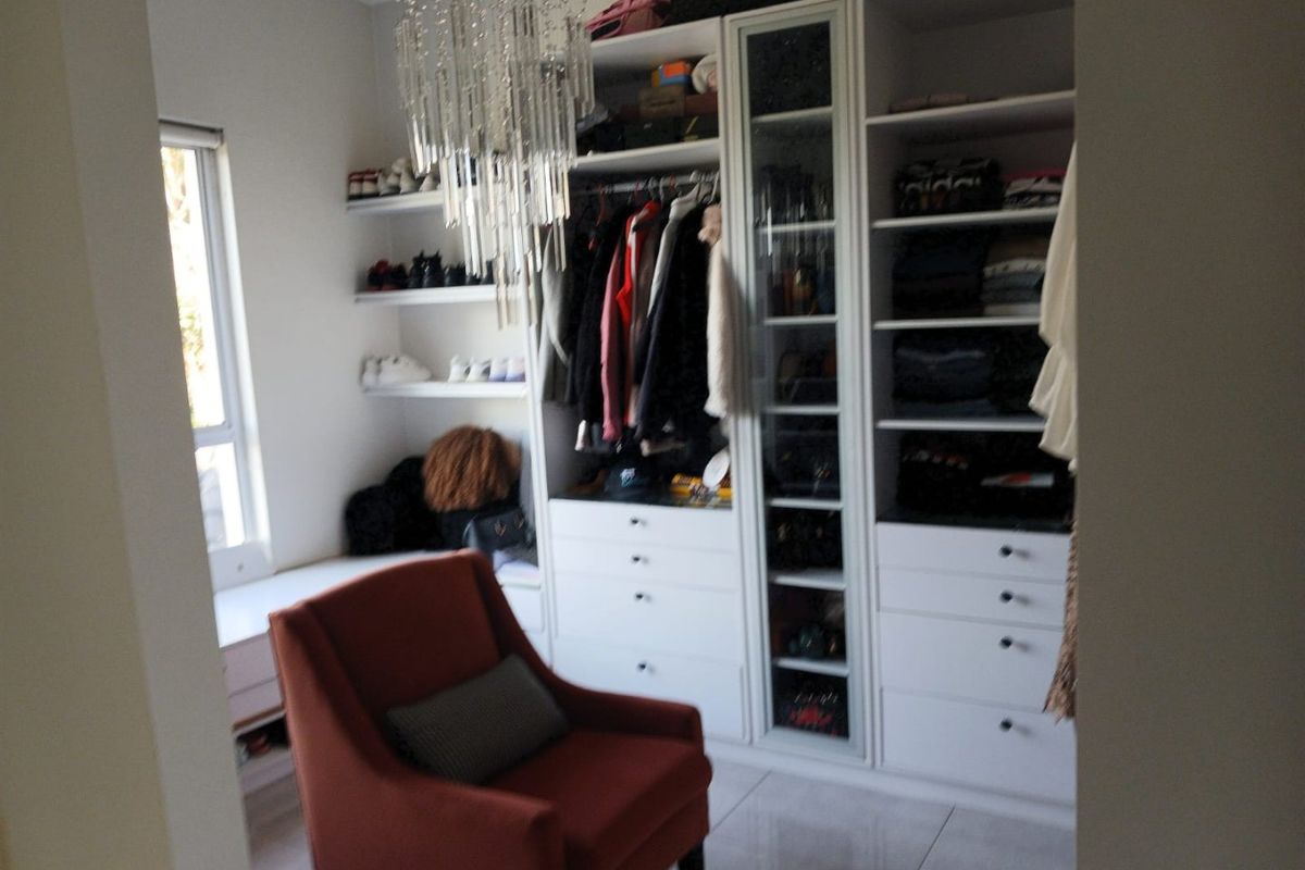 A well-organized walk-in closet featuring extensive built-in cabinetry, shelving, and drawers with a window providing natural light.