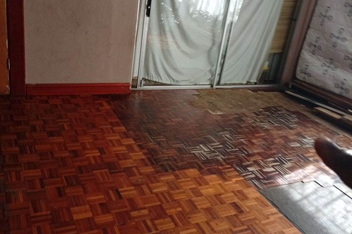 Living area featuring original parquet flooring in need of restoration and sliding glass doors providing access to the exterior.