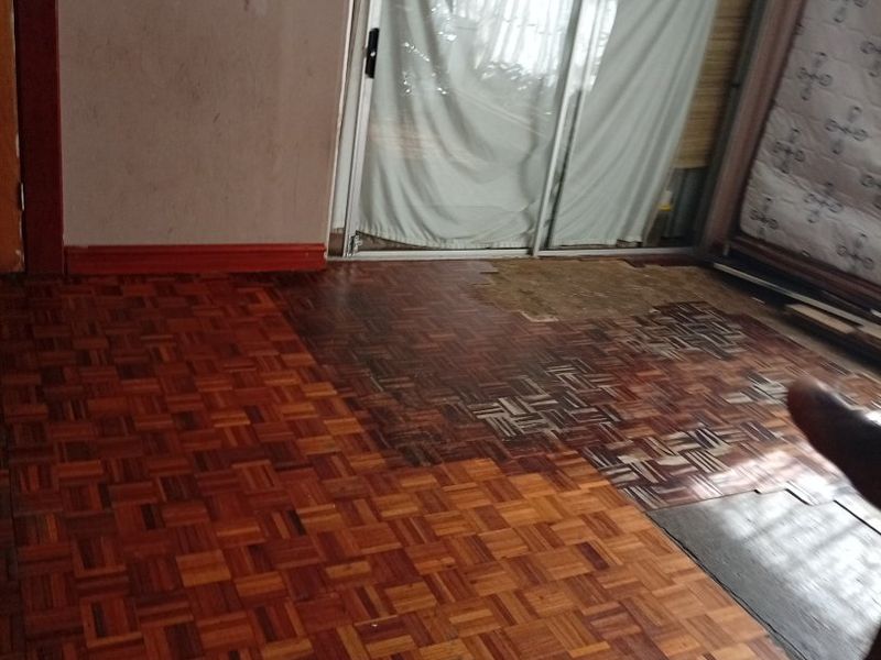 Living area featuring original parquet flooring in need of restoration and sliding glass doors providing access to the exterior.