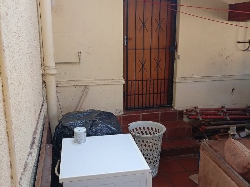 A utility area or covered patio space showing significant signs of wear, including damaged ceiling finishes and weathered wall surfaces.