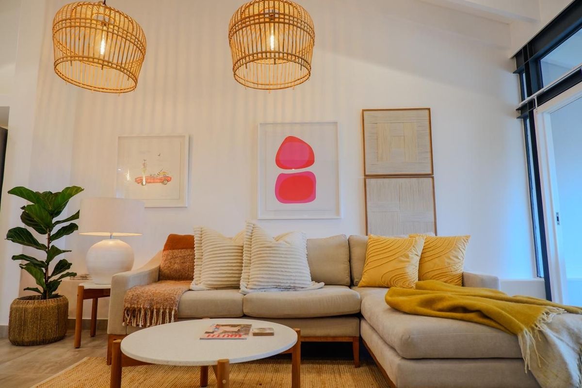 A bright living room featuring high vaulted ceilings, exposed structural beams, and large sliding glass doors leading to an outdoor area.
