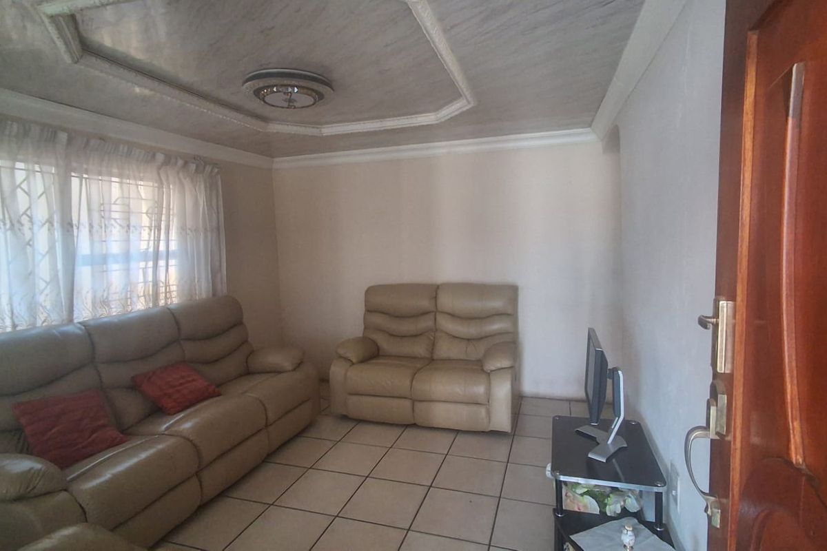 A living room featuring tiled flooring and a decorative tray ceiling with central lighting.