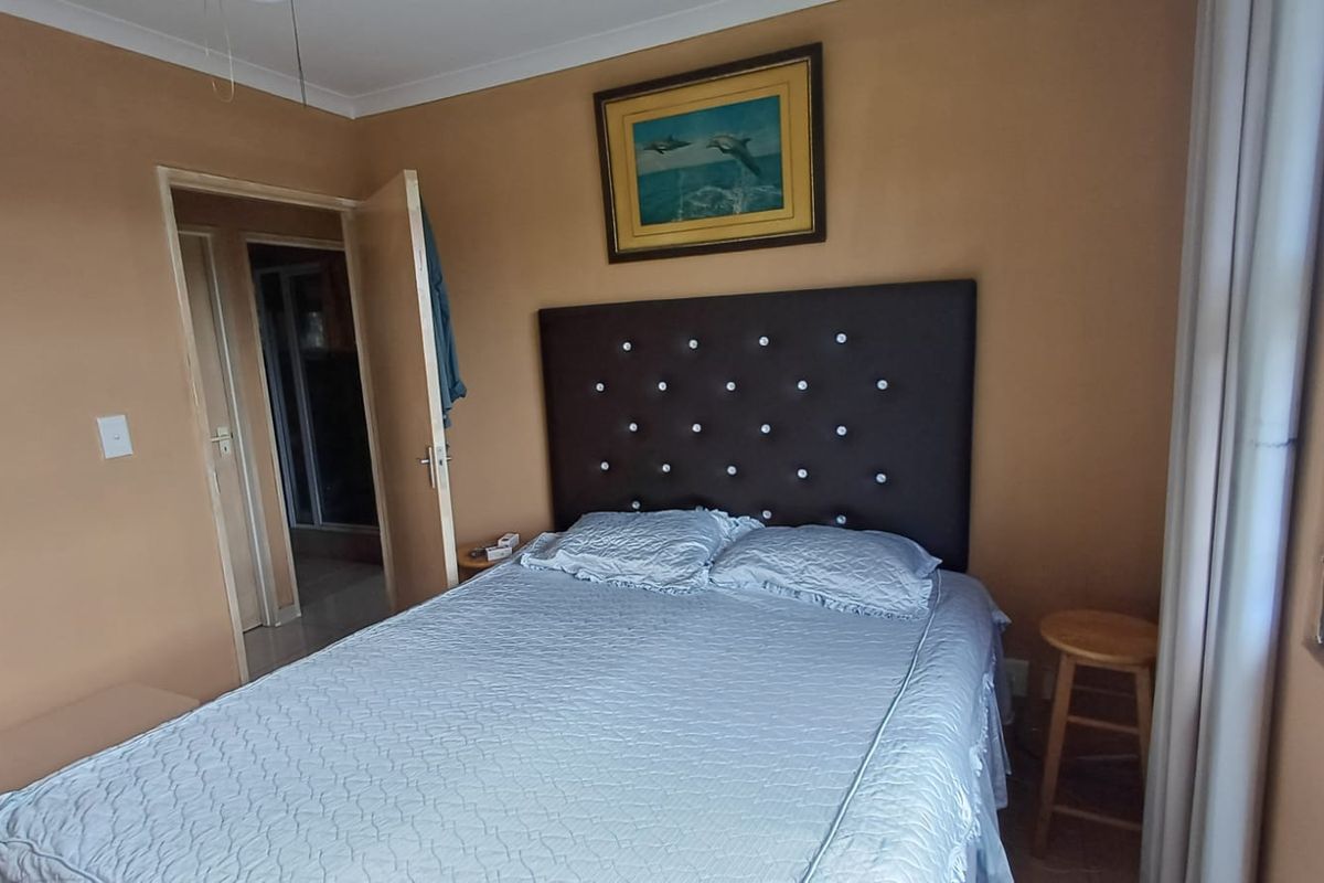 A bedroom featuring neutral wall tones, a window with security bars, and an adjoining doorway leading to an en-suite bathroom.