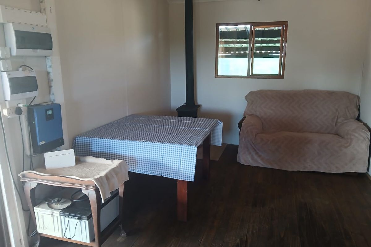A living area featuring dark timber flooring, a wood-burning fireplace, and wall-mounted electrical infrastructure including an inverter system.