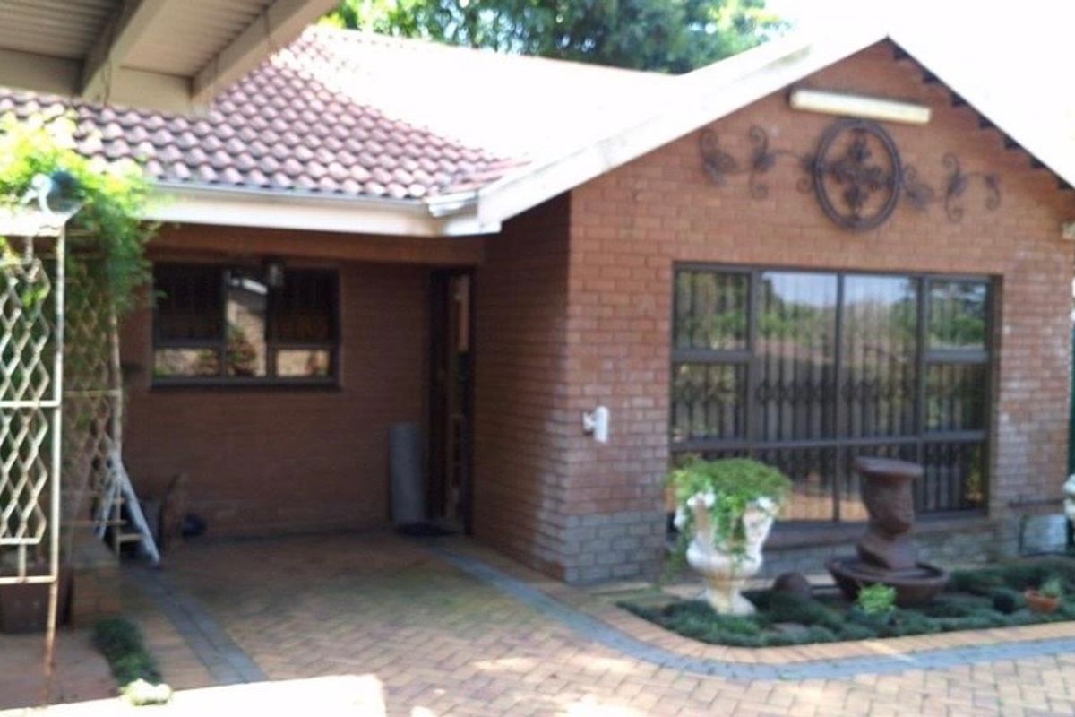 A view of the rear exterior of the house featuring a brick facade, tiled roof, paved patio area, and a water tank.