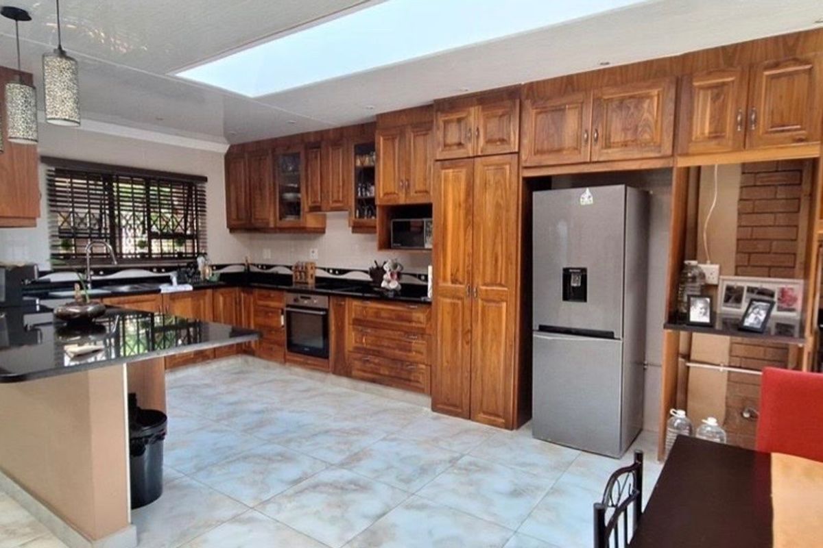 Spacious kitchen featuring solid wood cabinetry, black granite countertops, a breakfast bar, and a large skylight providing ample natural light.