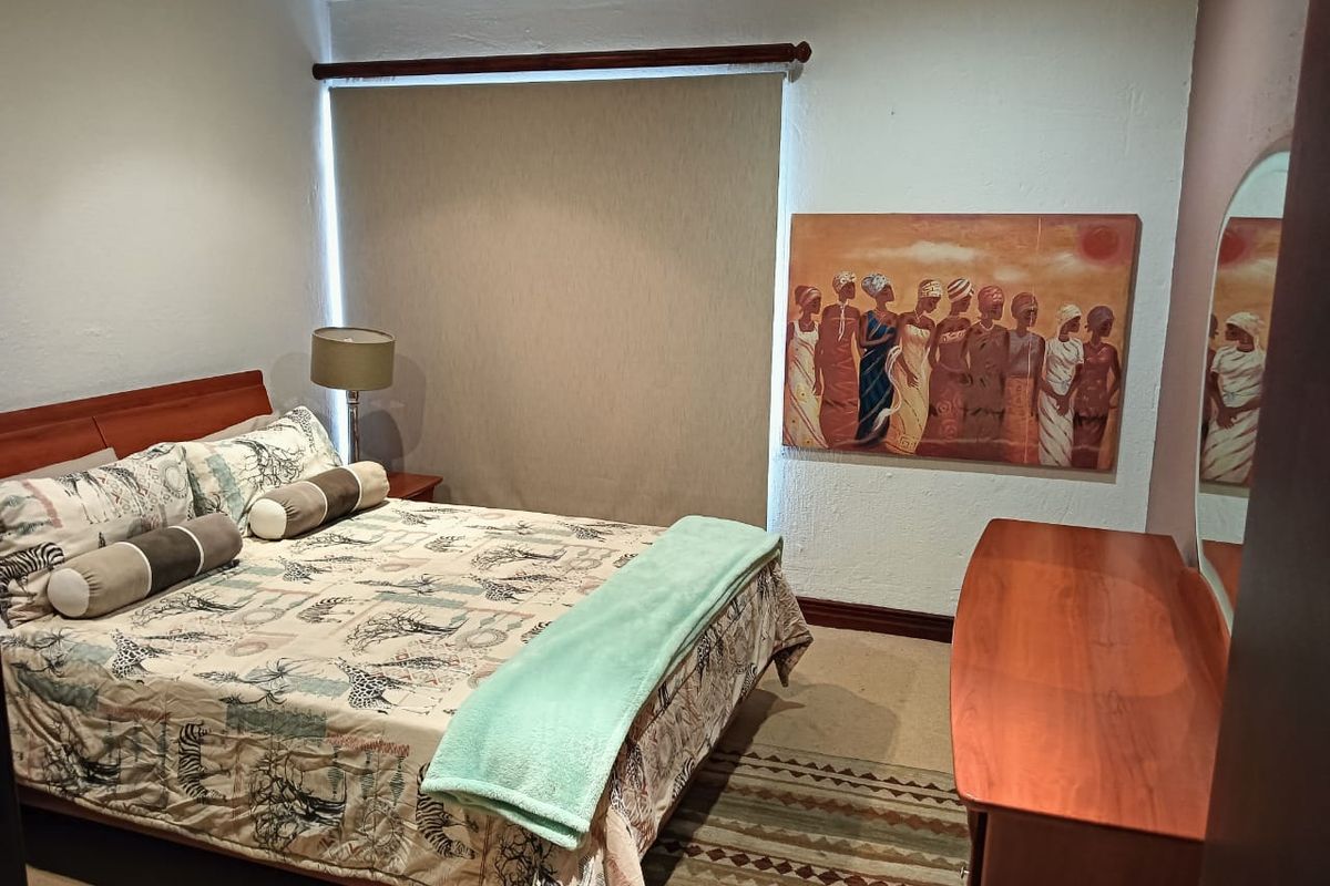 A well-maintained bedroom featuring neutral wall finishes, a roller blind, and a split-system air conditioning unit.