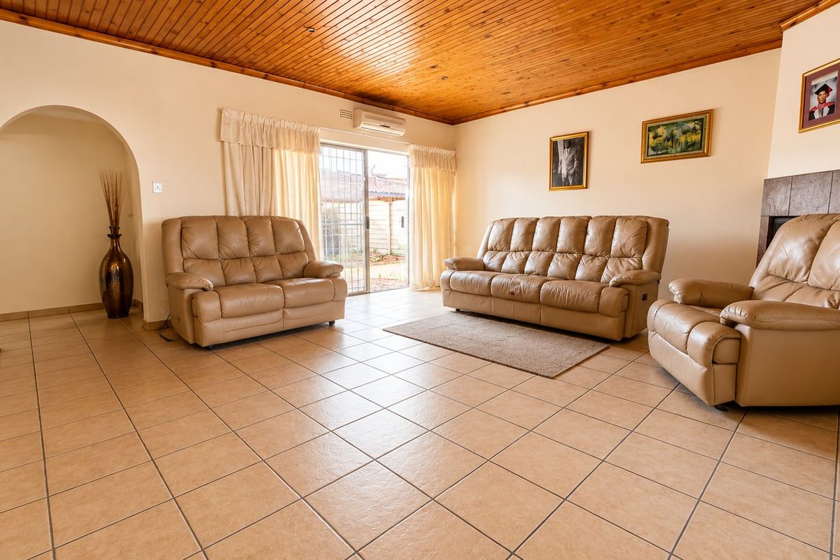 Spacious living room featuring tiled flooring, a timber-clad ceiling, and a built-in fireplace, with direct access to the outdoor area through sliding glass doors.