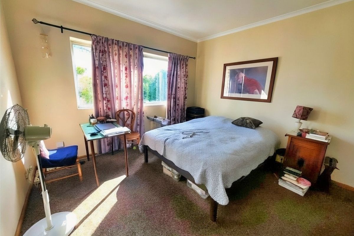 A bedroom featuring carpeted flooring, large windows with curtain rods, and coved ceiling detailing.