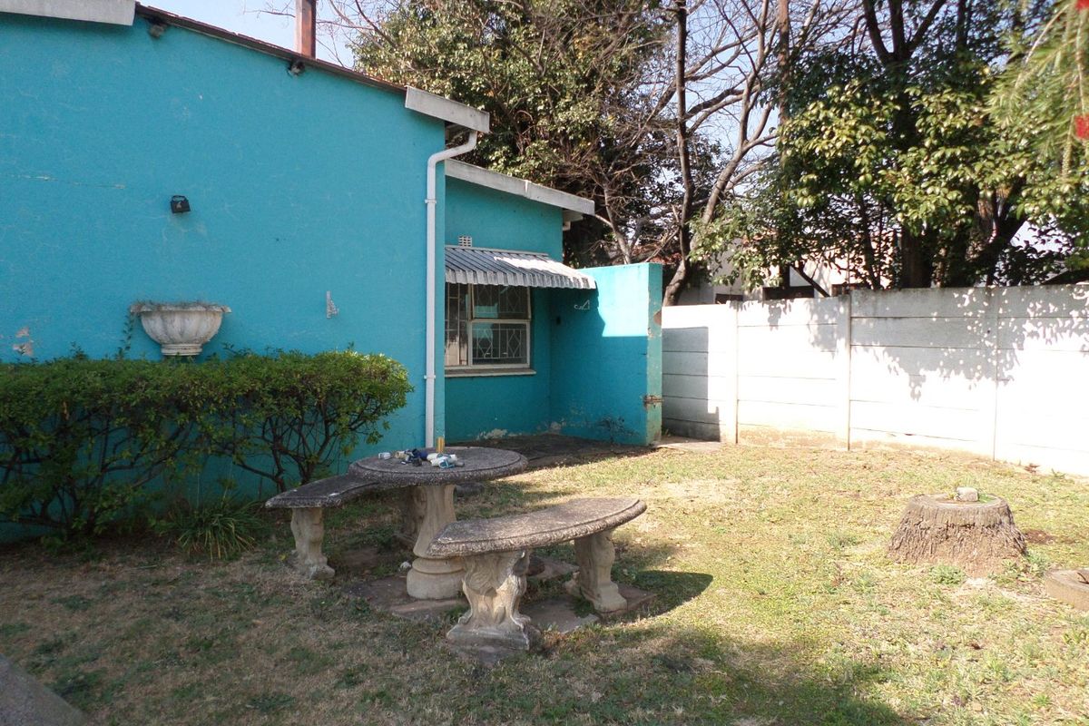 Rear garden area featuring a turquoise exterior wall, concrete patio furniture, and a perimeter boundary wall.