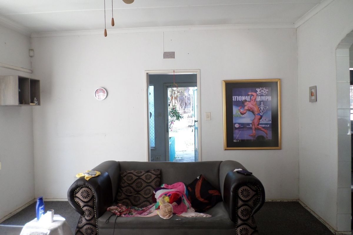A living room area featuring a central doorway leading to the exterior, with plain white walls and a ceiling fan.