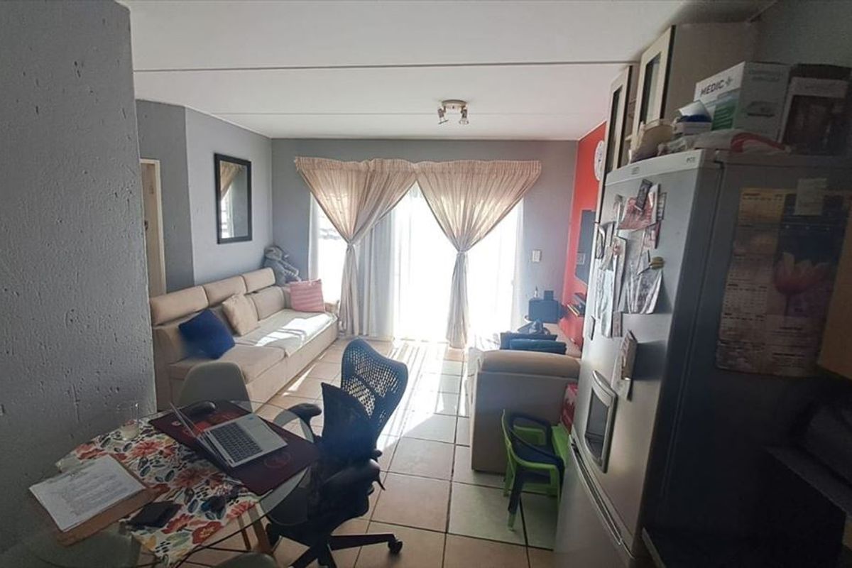 An open-plan living area featuring tiled flooring and sliding glass doors that provide access to the exterior.