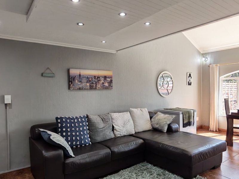 Open-plan living and dining area featuring tiled flooring, recessed downlighting, and an arched window providing natural light.