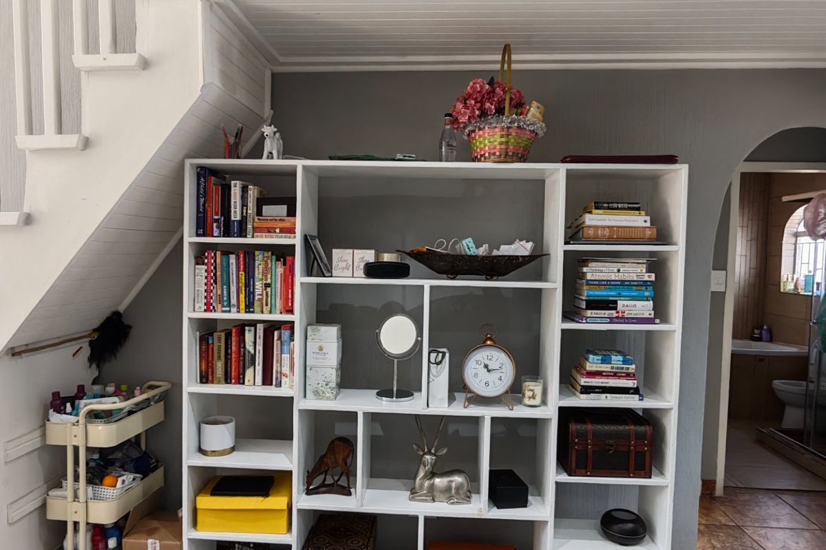 Living area featuring a staircase, built-in shelving unit, and an arched doorway leading to an adjacent room with tiled flooring.