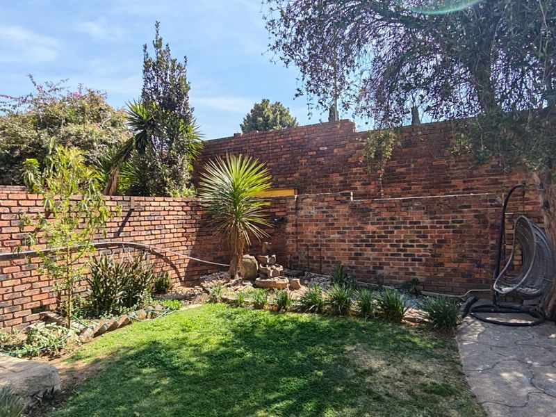 A private rear garden featuring a lawn, paved patio area, and established brick boundary walls.