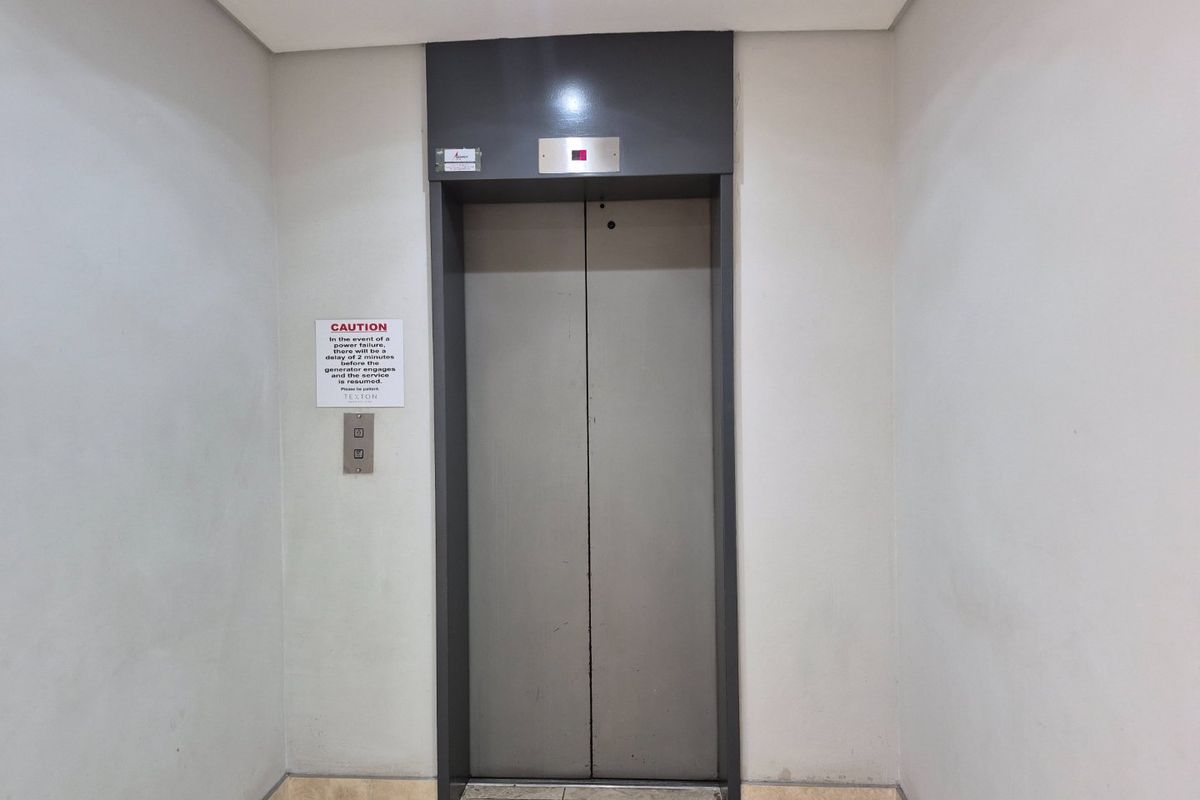 A commercial elevator lobby featuring tiled flooring and neutral wall finishes, providing access to the building's vertical transport system.