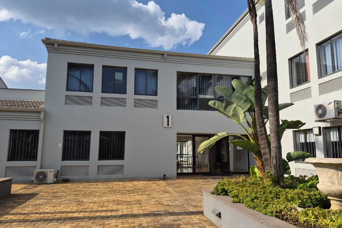 A well-maintained commercial building exterior featuring a paved courtyard, raised garden beds, and secure ground-floor access points.