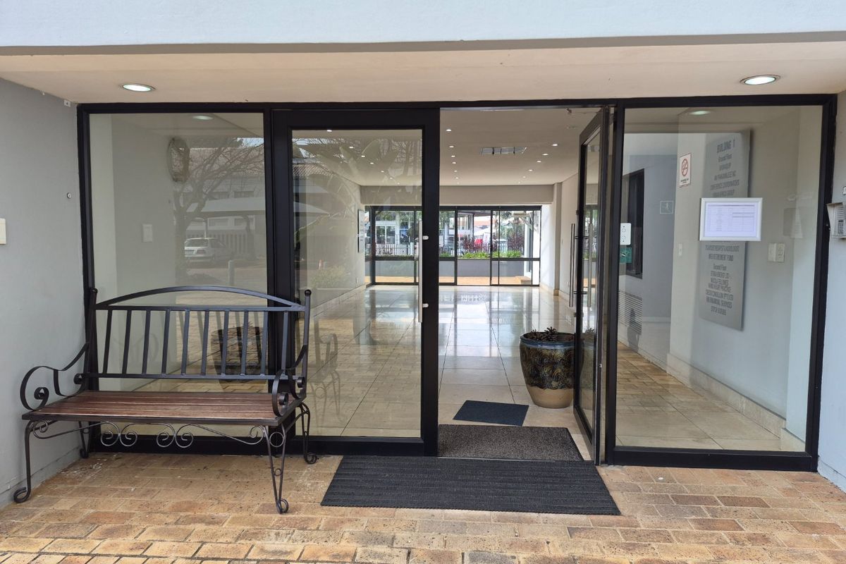 Commercial building entrance featuring glass sliding doors, tiled flooring, recessed lighting, and a directory board for tenants.