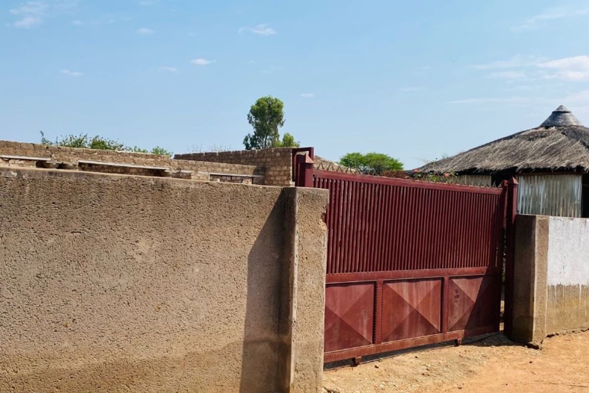 A view of the property entrance featuring a solid perimeter wall and a metal gate.