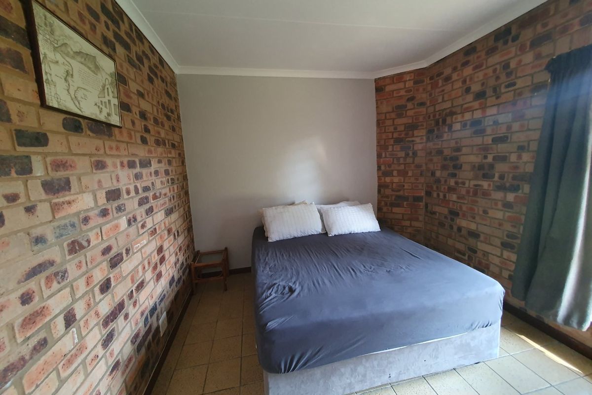 A bedroom featuring exposed brick walls and tiled flooring, providing a rustic aesthetic with a neutral color palette.