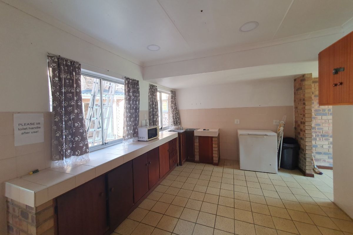 A functional kitchen featuring brick-based cabinetry, tiled countertops, and tiled flooring, offering a dated aesthetic with potential for modernization.