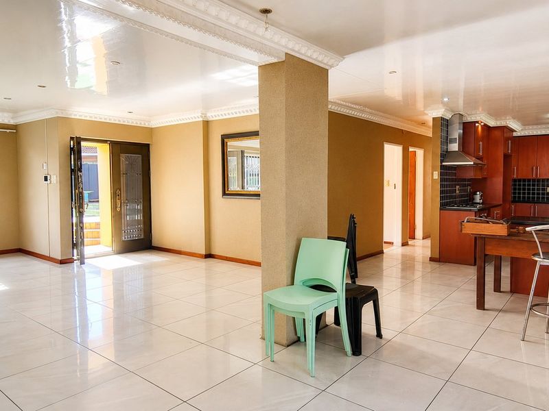 Spacious open-plan living and kitchen area featuring tiled floors, recessed lighting, and a functional kitchen layout with built-in cabinetry and a central island.
