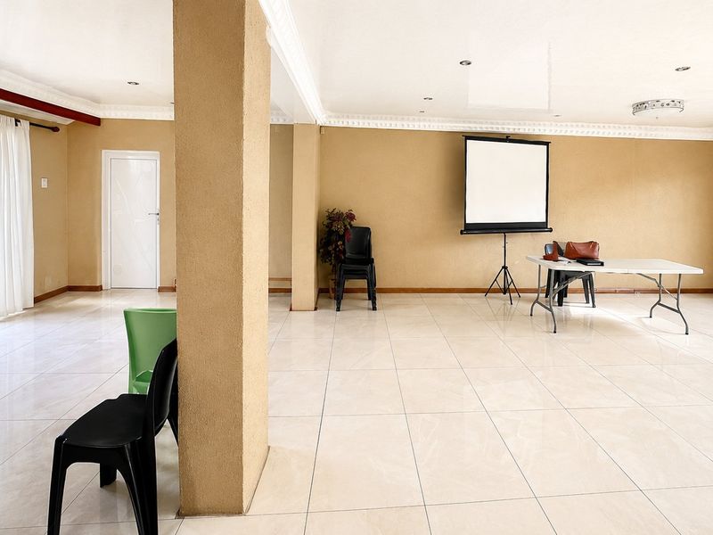 Spacious open-plan living area featuring neutral wall tones, large format floor tiles, decorative ceiling cornices, and access to the exterior via a sliding door.