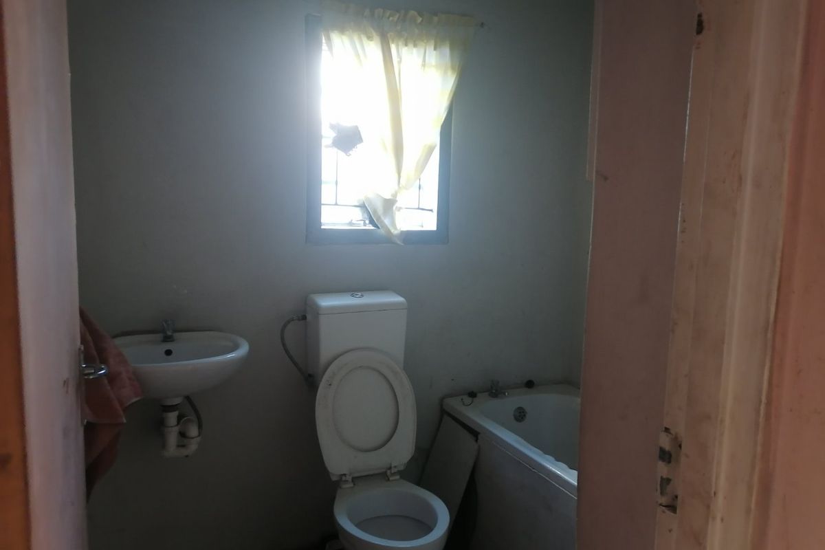 A dated bathroom featuring a wall-mounted basin, toilet, and bathtub, requiring cosmetic updates to improve its overall condition and appeal.