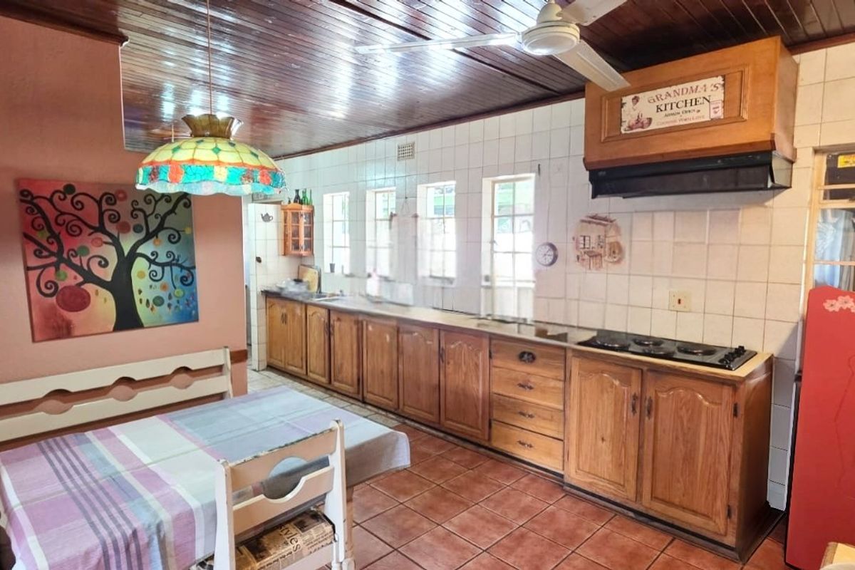 A traditional kitchen featuring wooden cabinetry, a tiled backsplash, built-in hob with extractor fan, and a timber ceiling.