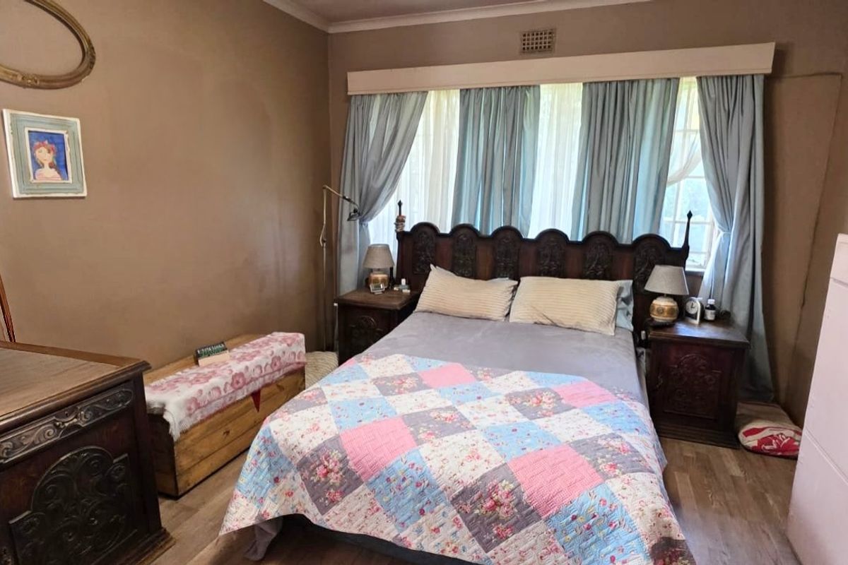 A bedroom featuring laminate flooring, a curtain pelmet, and a ceiling vent, offering a functional space with potential for modern updates.