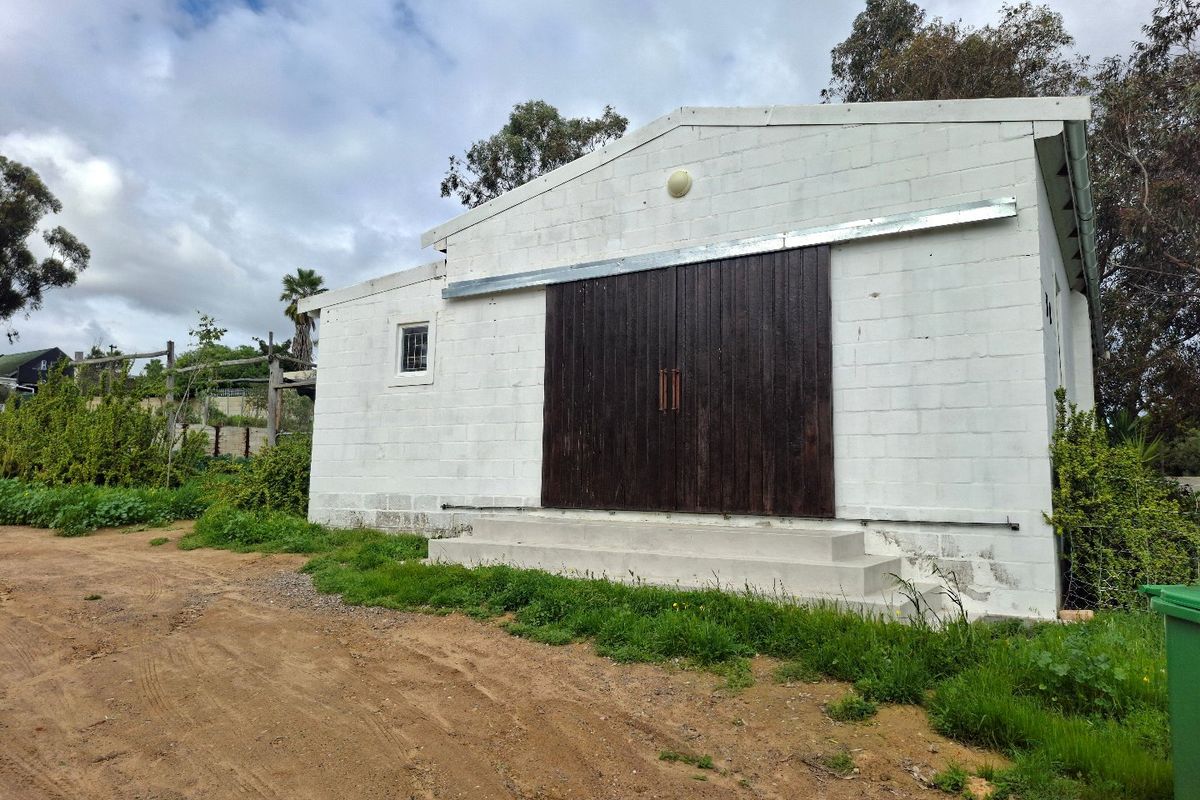 Exterior view of a detached outbuilding featuring concrete block construction, large sliding barn doors, and concrete entry steps.