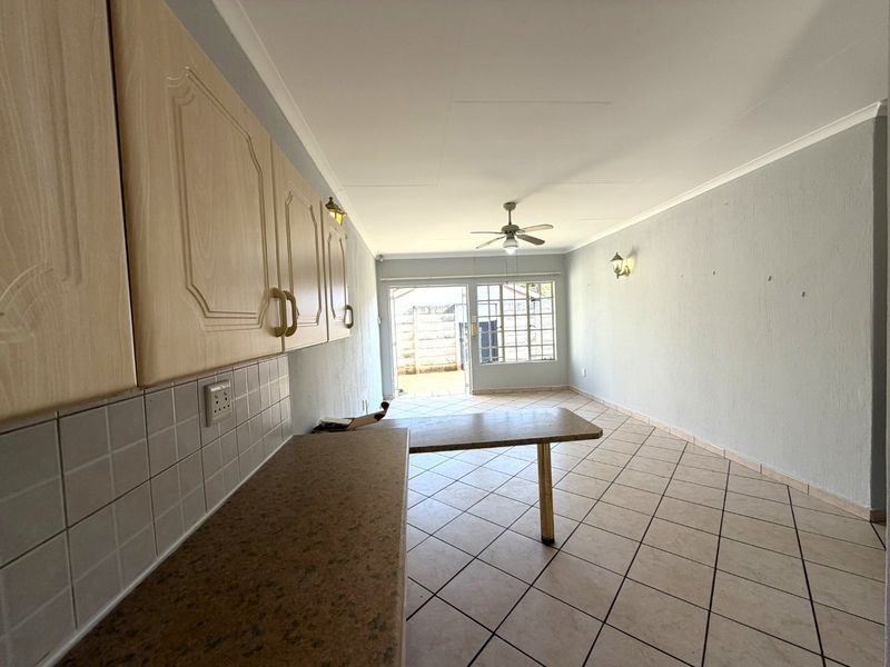 An open-plan living and kitchen area featuring tiled flooring, built-in cabinetry, and a sliding door leading to the exterior.