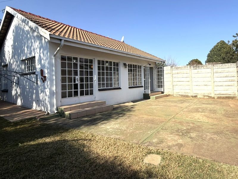 Rear view of the apartment featuring a concrete patio area, tiled roof, and secure precast boundary walling with access via french doors.