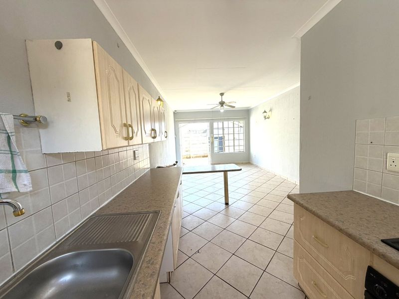Open-plan kitchen and living area featuring tiled flooring, neutral walls, and direct access to an outdoor space through sliding glass doors.