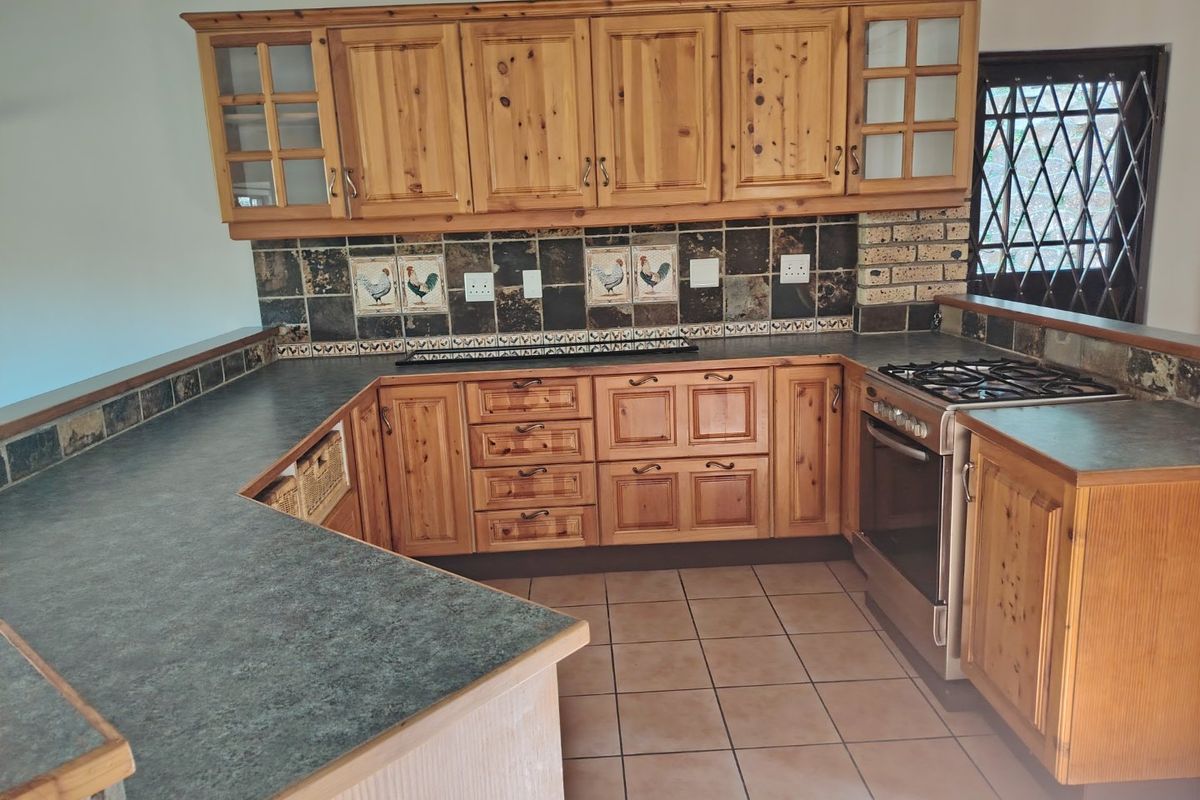 A functional kitchen featuring wooden cabinetry, laminate countertops, a gas stove, and decorative tiled backsplash, offering a traditional aesthetic ready for modernization.
