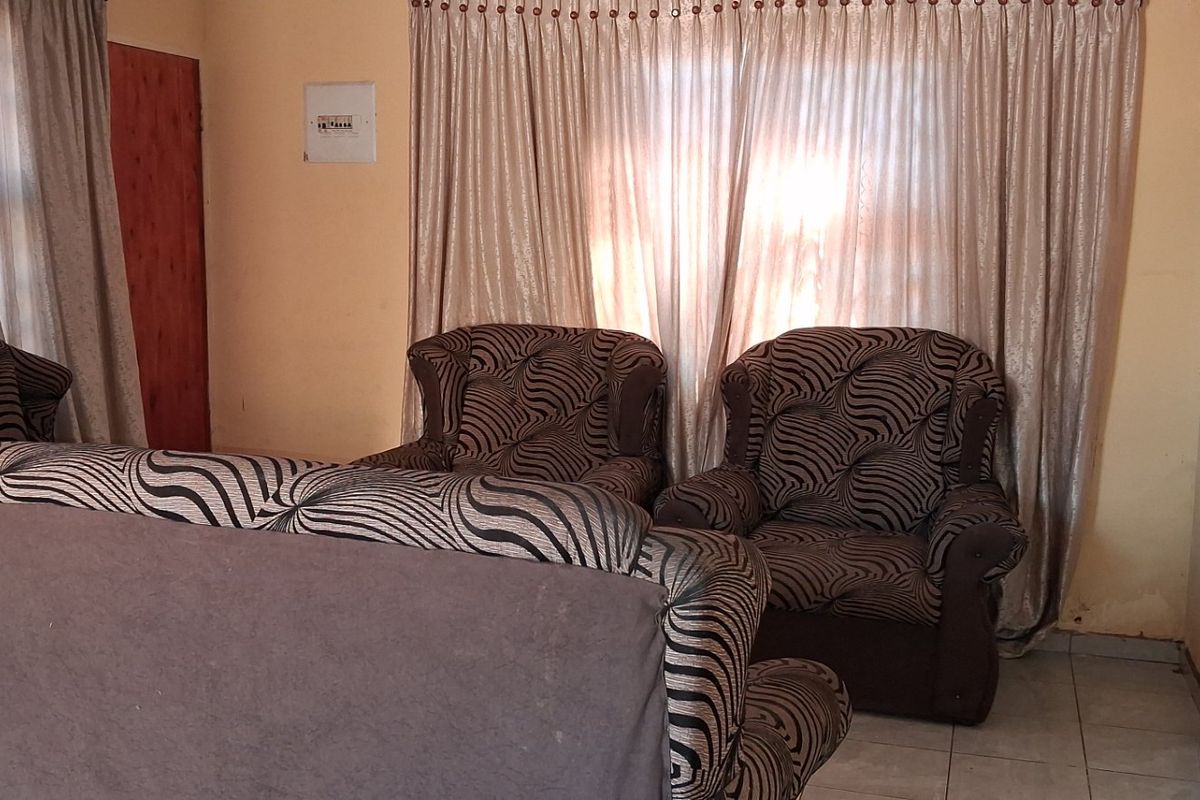 A living room area featuring tiled flooring and wall-mounted electrical fixtures, showing signs of wear and requiring cosmetic updates.