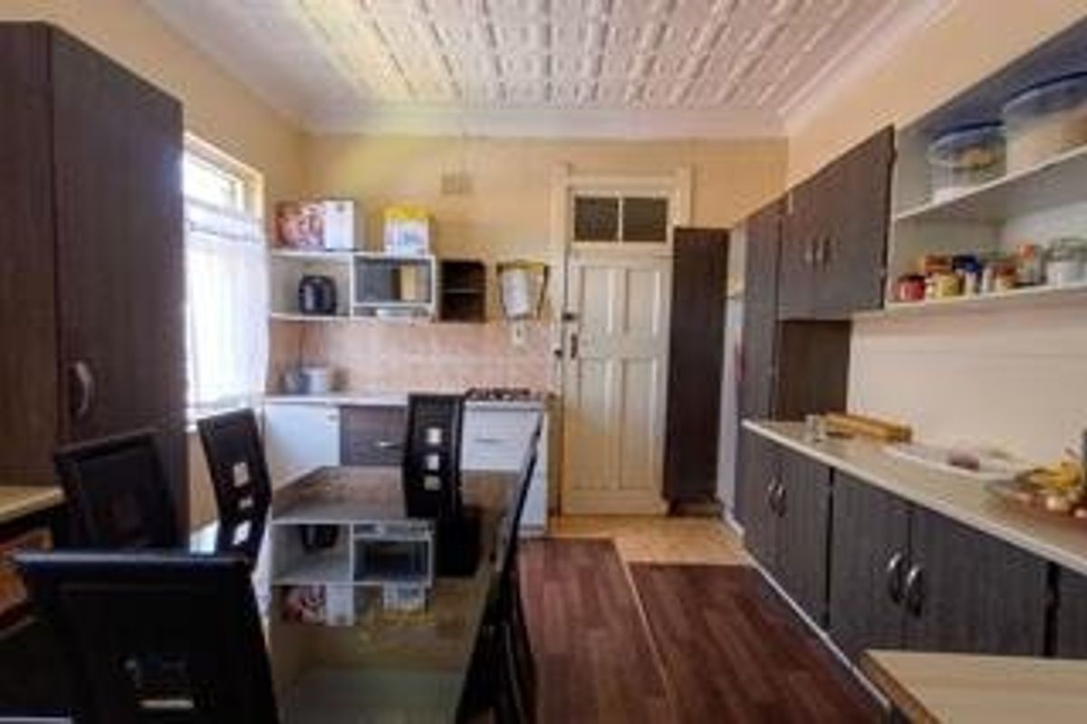 A functional kitchen featuring dark built-in cabinetry, laminate flooring, a tiled backsplash, and a distinctive pressed metal ceiling.