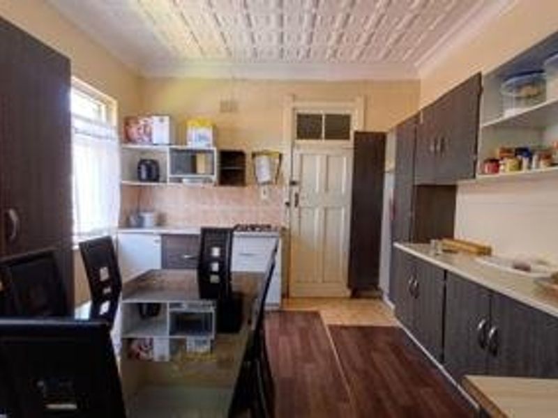 A functional kitchen featuring dark built-in cabinetry, laminate flooring, a tiled backsplash, and a distinctive pressed metal ceiling.