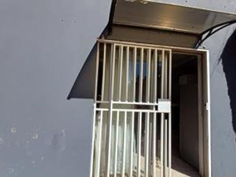 Exterior view of the property entrance featuring a security gate and a protective awning over the doorway.