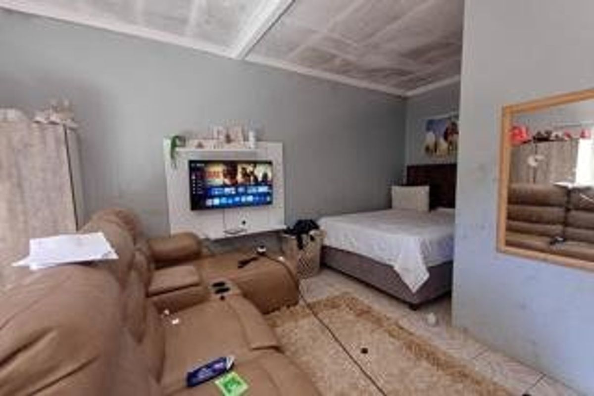 A bedroom featuring tiled flooring and a built-in media unit, showing signs of wear on the ceiling and walls.