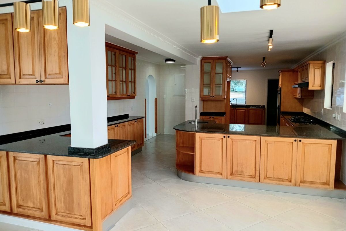 Spacious kitchen featuring extensive wooden cabinetry, granite countertops, a central island, and integrated appliances, offering a functional layout with ample storage and workspace.