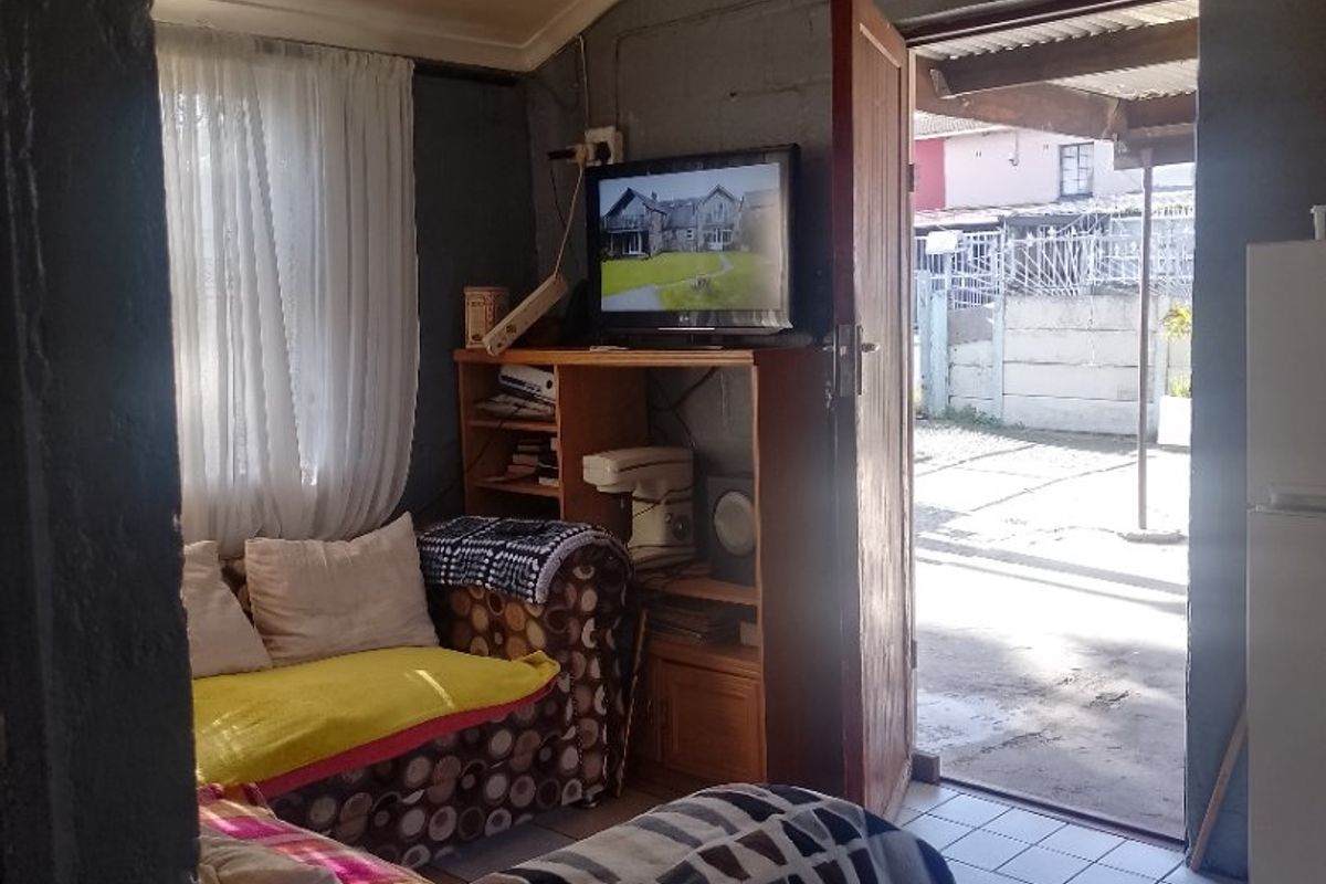 A compact living area featuring tiled flooring and direct access to the exterior, requiring cosmetic updates to improve the overall finish and aesthetic.