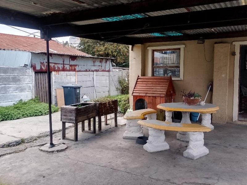 Covered outdoor patio area featuring a corrugated metal roof, concrete flooring, and direct access to the rear garden space.
