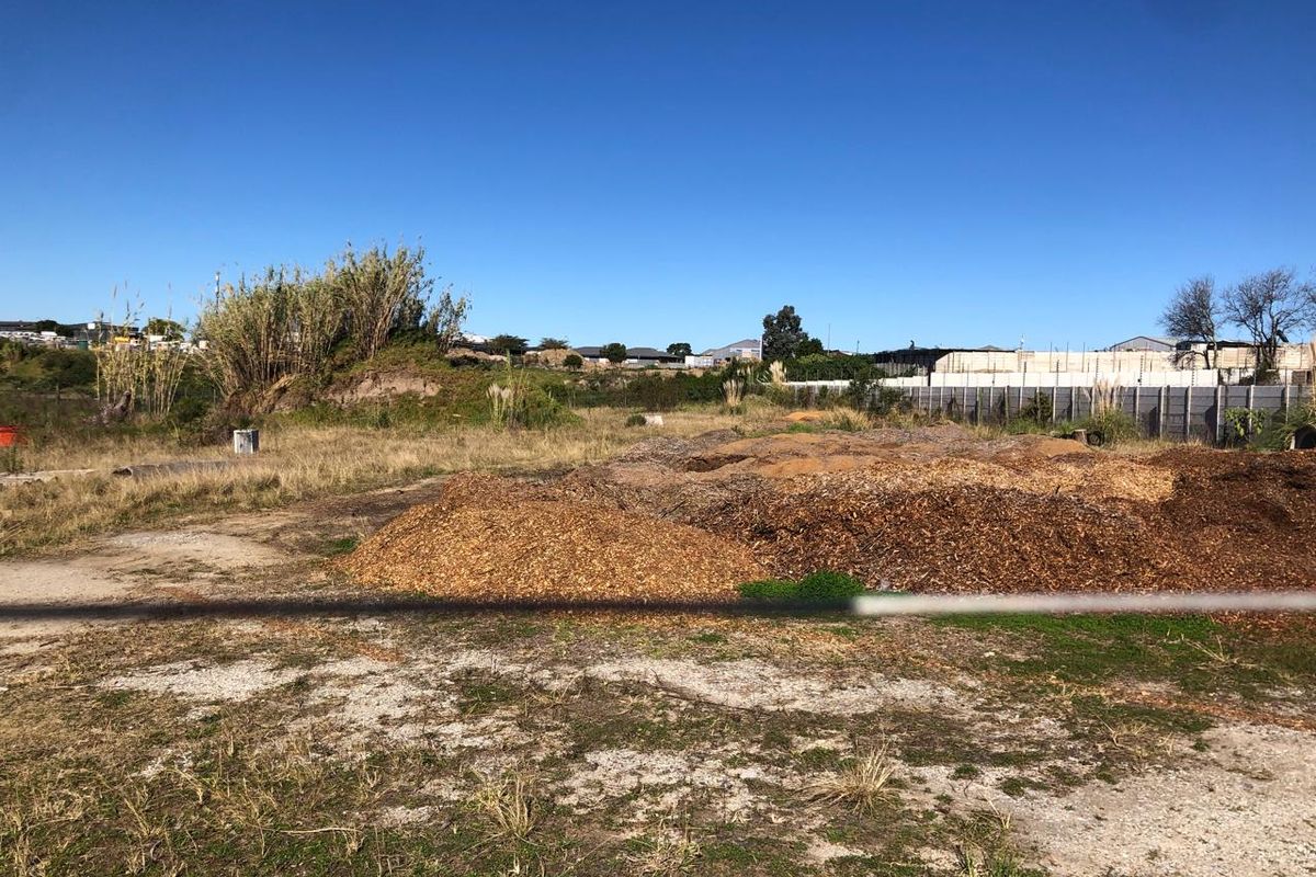 An undeveloped industrial plot featuring open land, perimeter fencing, and electric security fencing, suitable for future development or storage.